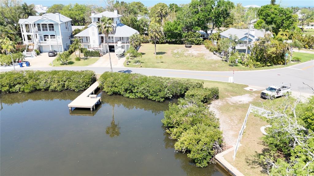 An aerial view shows a waterfront property with a dock, mangroves, and nearby houses — 231 LAGOON DRIVE, PALM HARBOR, FL