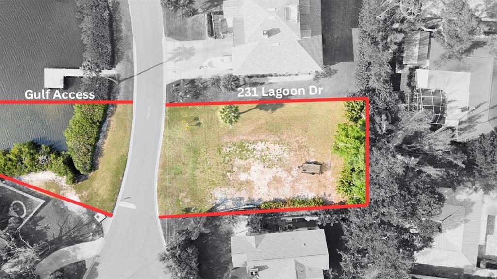 This aerial view shows a vacant residential lot outlined in red next to a canal — 231 LAGOON DRIVE, PALM HARBOR, FL
