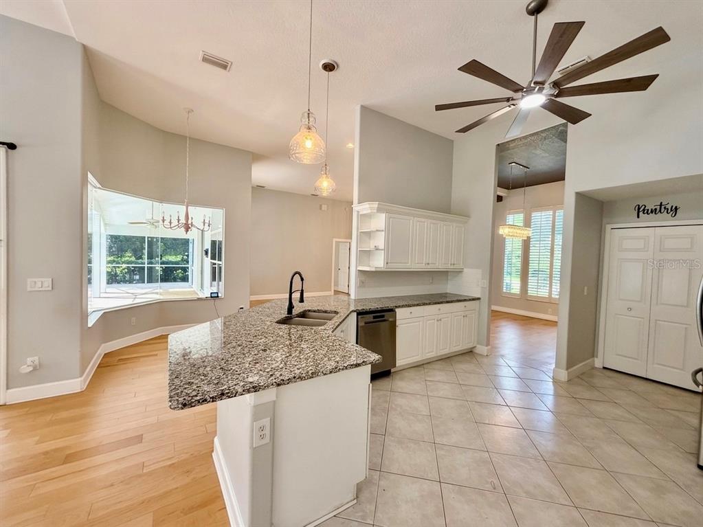 A kitchen features granite countertops, white cabinetry, a ceiling fan, and tile flooring — 63 BAY LAKE DRIVE, ORMOND BEACH, FL