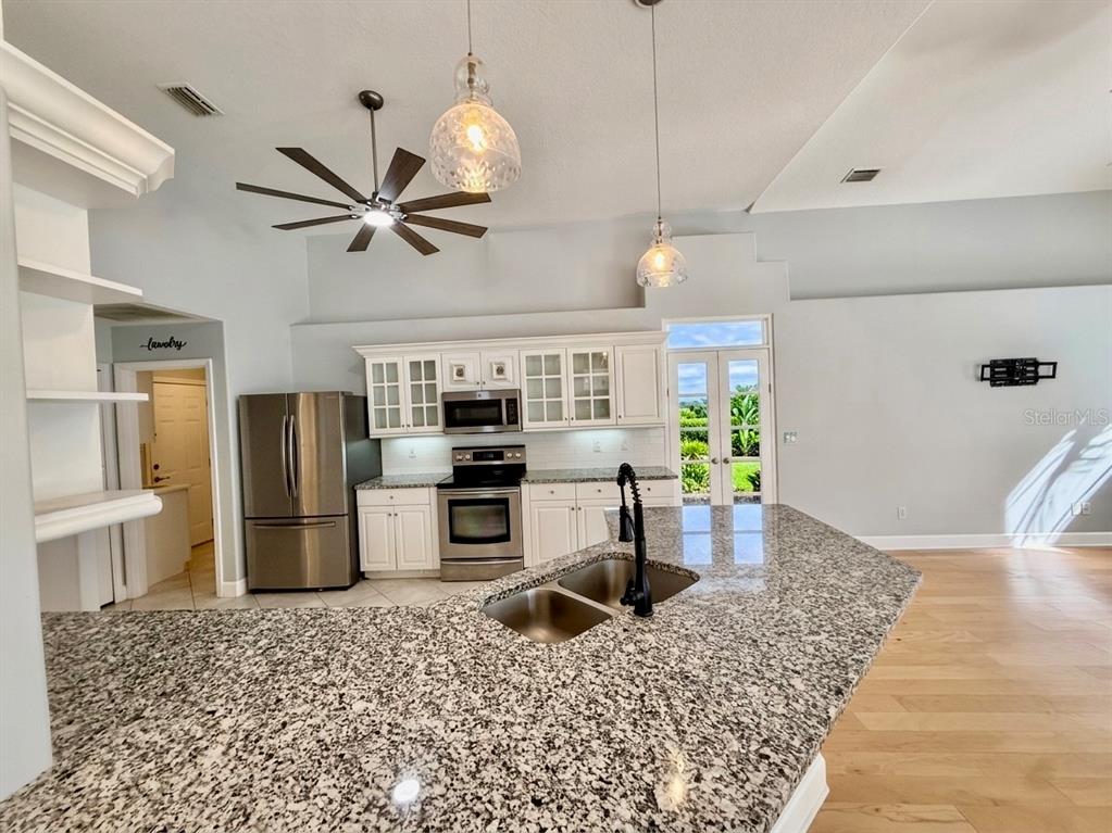 A kitchen features granite countertops, white cabinets, stainless steel appliances, and a large island — 63 BAY LAKE DRIVE, ORMOND BEACH, FL