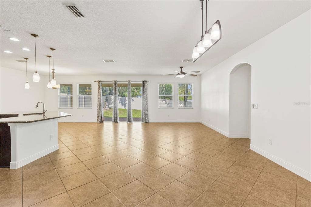 An open-concept living and dining area features tile flooring, a kitchen island, and sliding doors — 6706 RIVERSIDE BLUFFS DRIVE, RIVERVIEW, FL