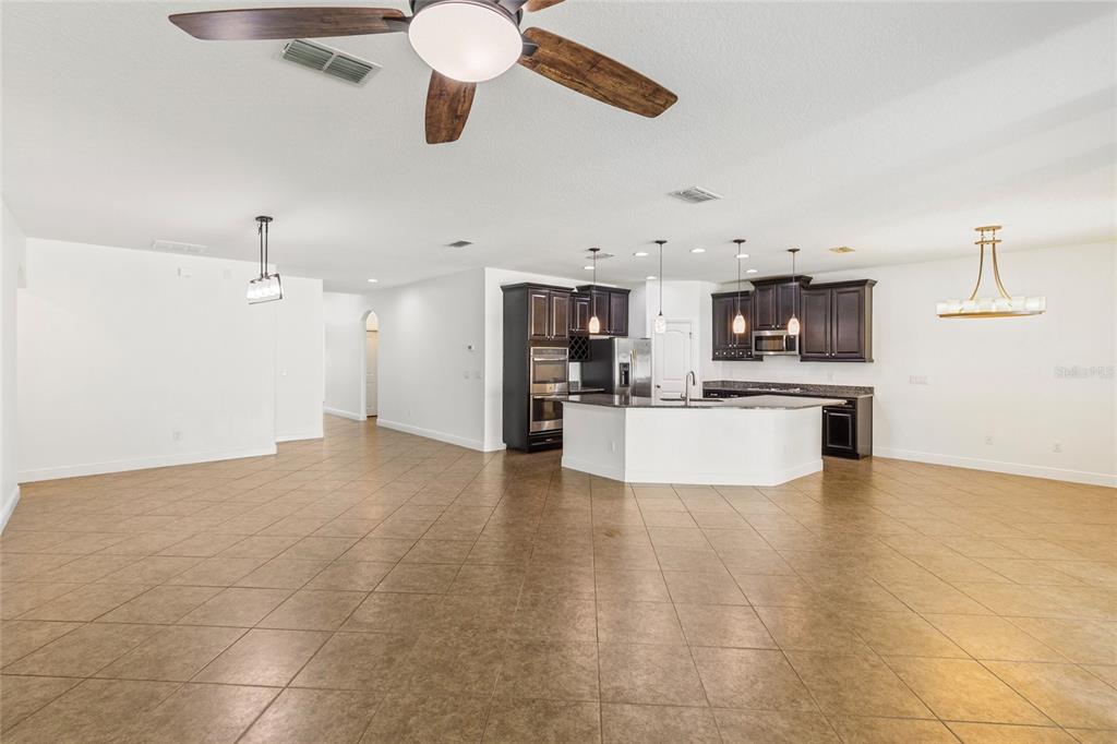 An open-concept kitchen features dark wood cabinetry, a central island, and tile flooring — 6706 RIVERSIDE BLUFFS DRIVE, RIVERVIEW, FL
