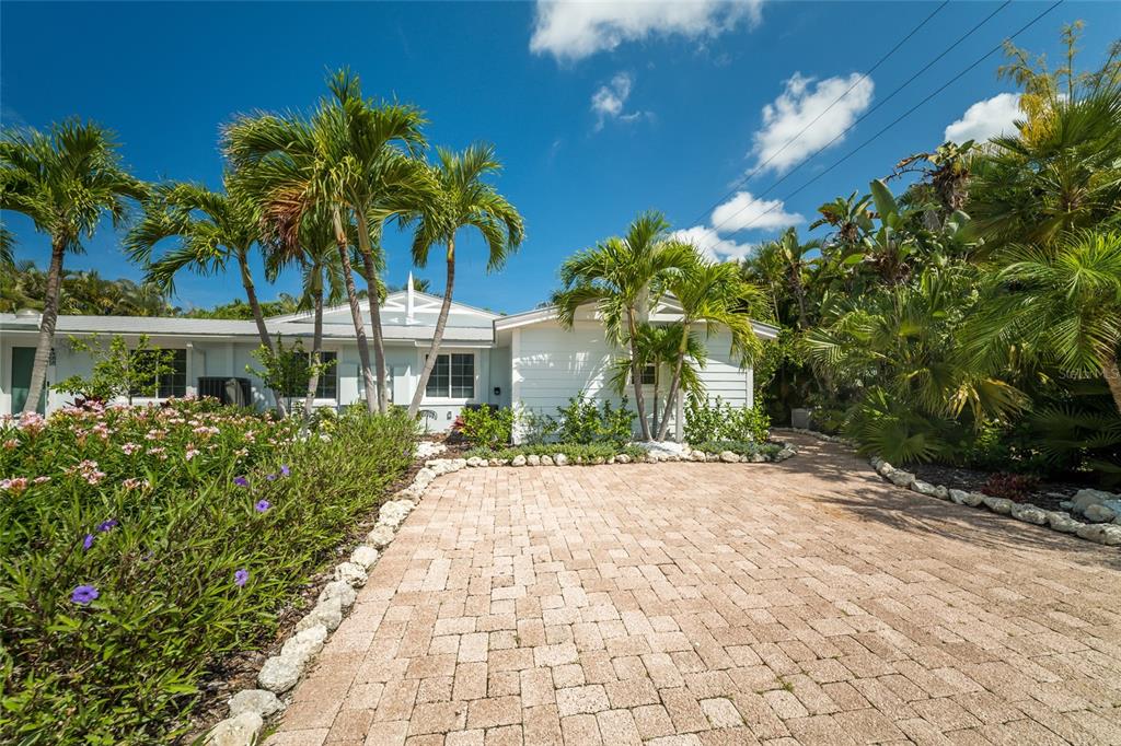 A paved driveway leads to a white house surrounded by palm trees and lush landscaping — 324 64TH STREET, HOLMES BEACH, FL