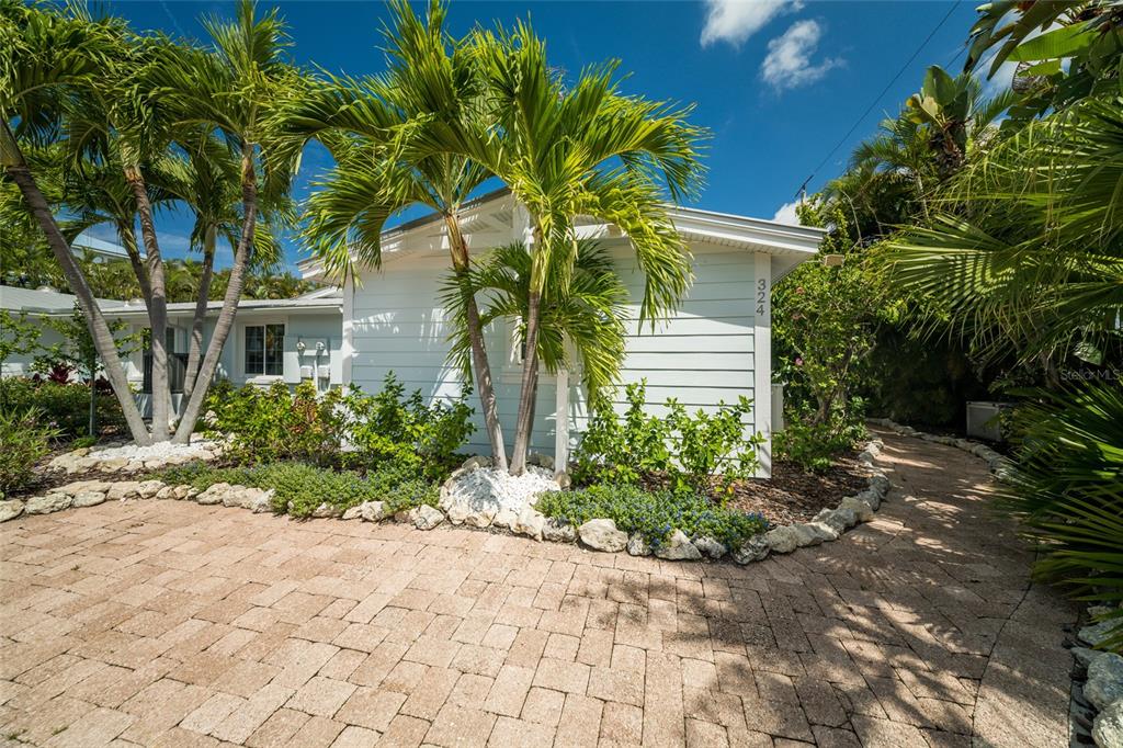 A light blue house with white trim sits behind a paved driveway and palm trees — 324 64TH STREET, HOLMES BEACH, FL