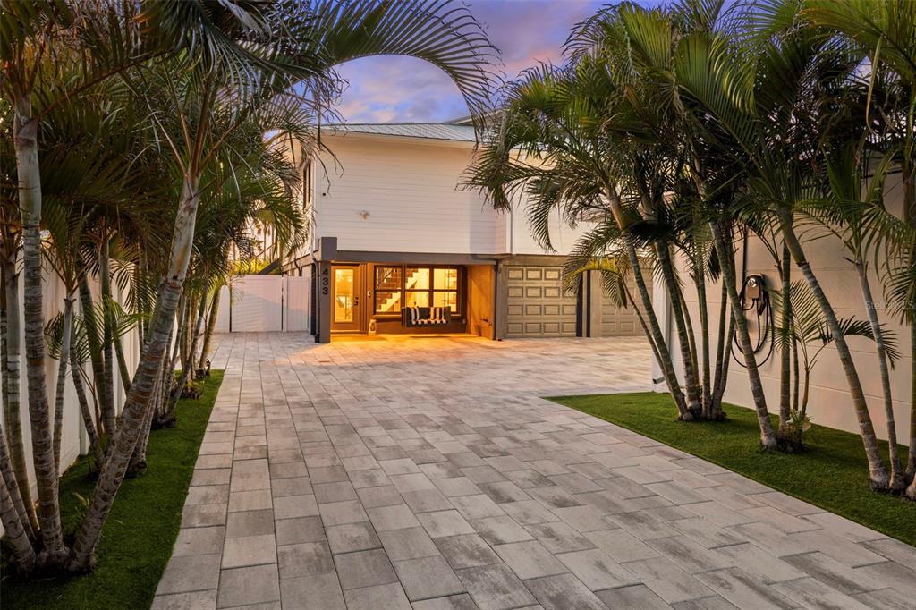 A paved driveway leads to a white house with a garage and palm trees — 439 CAUSEWAY BOULEVARD, DUNEDIN, FL