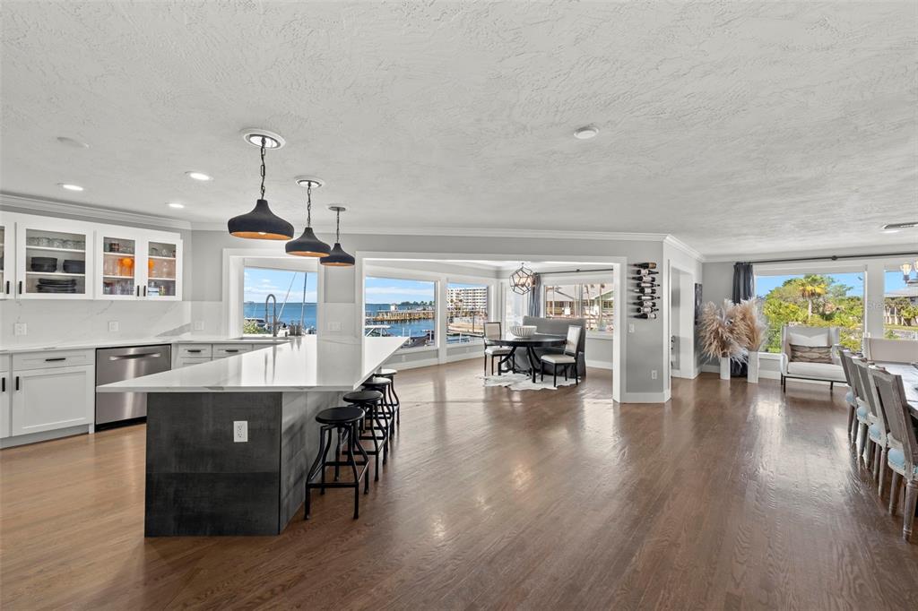 A bright, open-concept kitchen and dining area features a large island, hardwood floors, and waterfront views — 439 CAUSEWAY BOULEVARD, DUNEDIN, FL