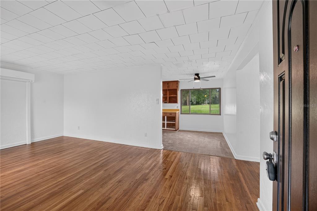 An interior view shows a living room with hardwood floors leading to a carpeted dining area — 5514 SE HAMES ROAD, BELLEVIEW, FL
