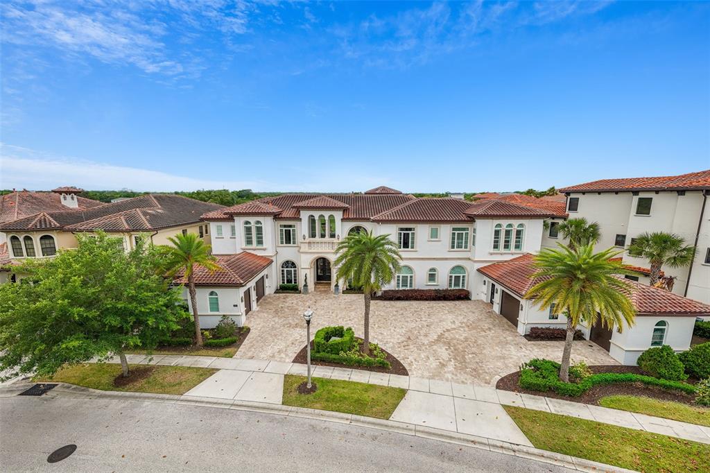An aerial view of a large Mediterranean-style house with a paved driveway and palm trees — 430 MUIRFIELD LOOP, REUNION, FL
