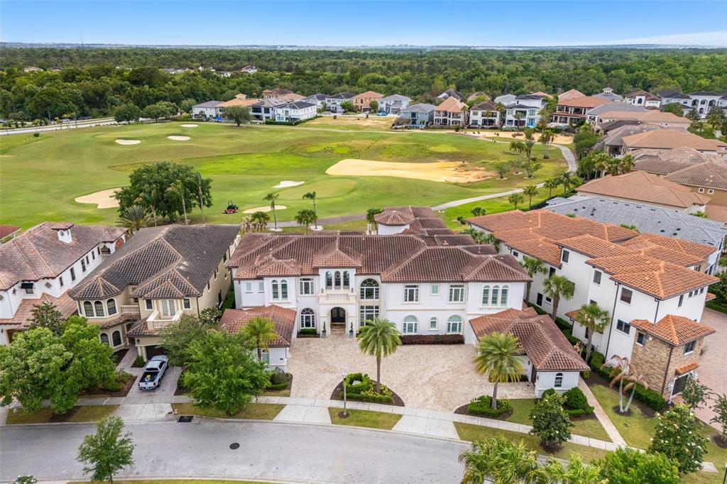 An aerial view shows a large Mediterranean-style house with a tiled roof and golf course — 430 MUIRFIELD LOOP, REUNION, FL