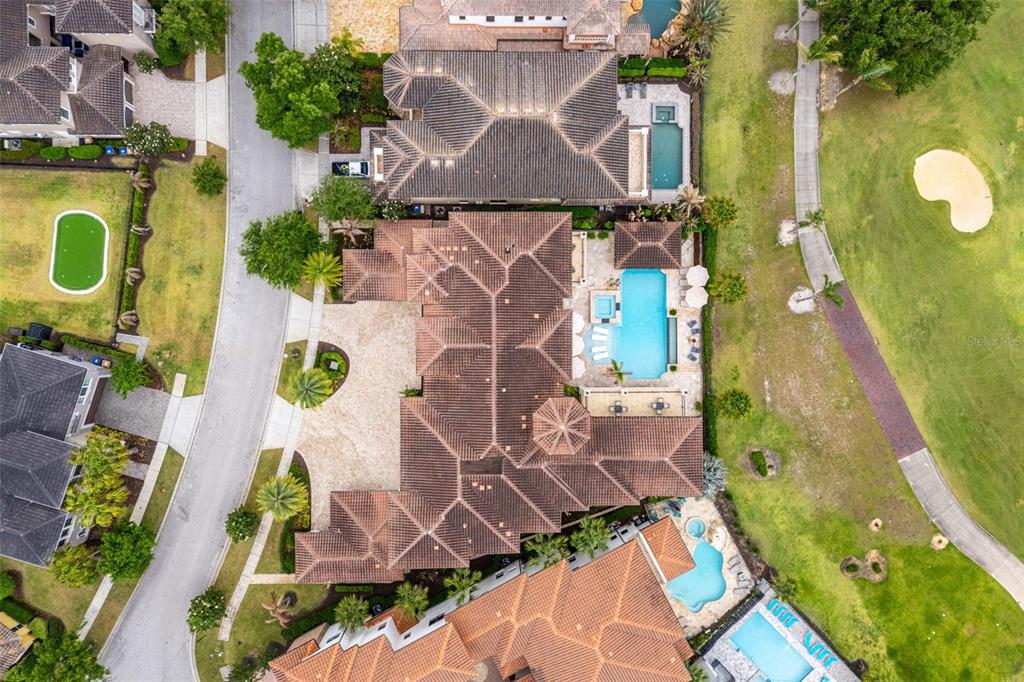 An aerial view shows a large house with a tiled roof, pool, and golf course — 430 MUIRFIELD LOOP, REUNION, FL