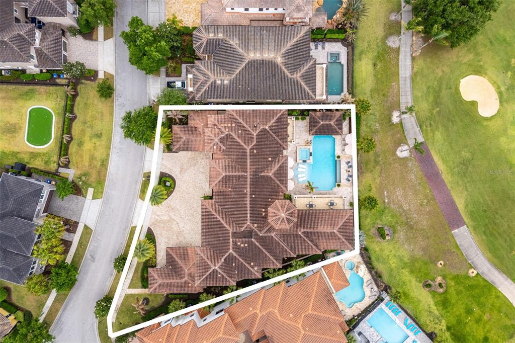 This aerial view shows a large house with a tiled roof, pool, and patio — 430 MUIRFIELD LOOP, REUNION, FL