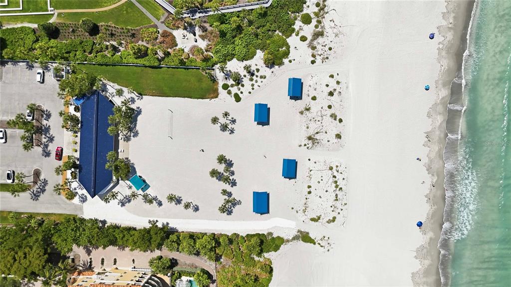 An aerial view shows a beachside building with parking, sand, cabanas, and the ocean — 3301 BAYOU ROAD, LONGBOAT KEY, FL