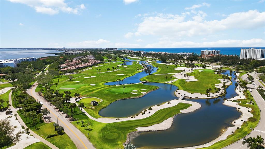 An aerial view of a golf course featuring multiple ponds, sand traps, and surrounding residential buildings — 3301 BAYOU ROAD, LONGBOAT KEY, FL