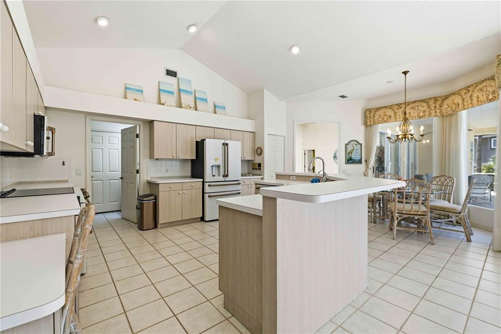 A kitchen with light wood cabinets, tile flooring, and a breakfast bar overlooks a dining area — 3301 BAYOU ROAD, LONGBOAT KEY, FL