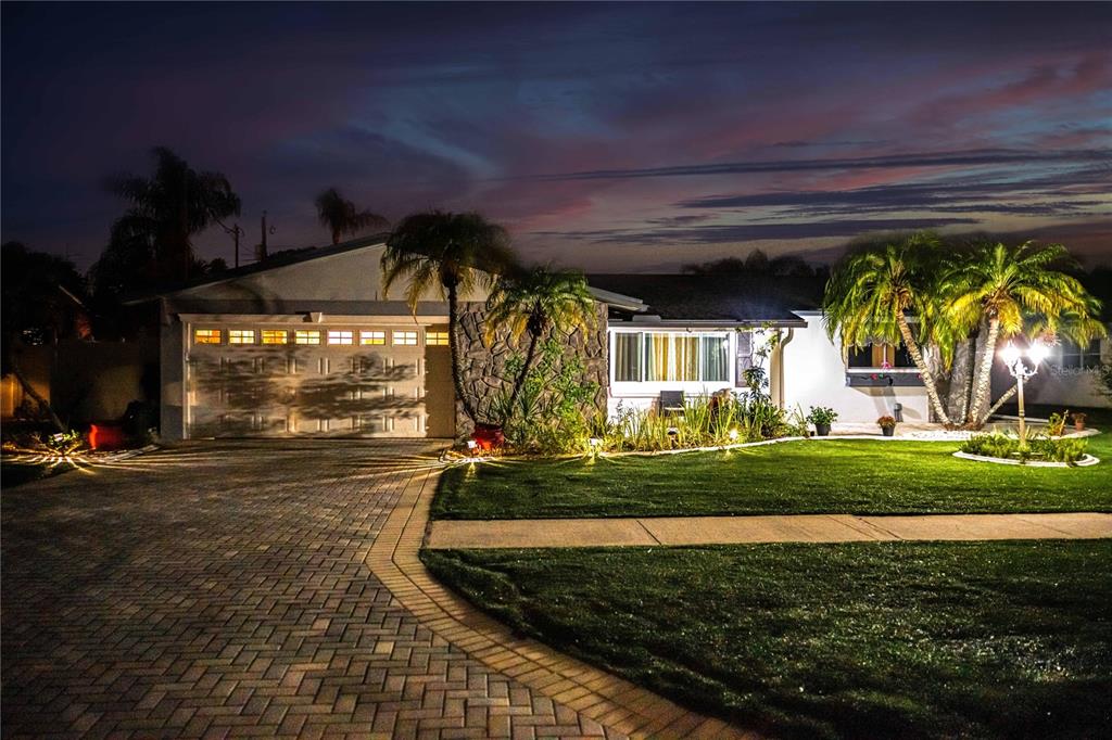 A single-story house with a stone facade, palm trees, and a paved driveway at night — 898 CORVETTE DRIVE, LARGO, FL