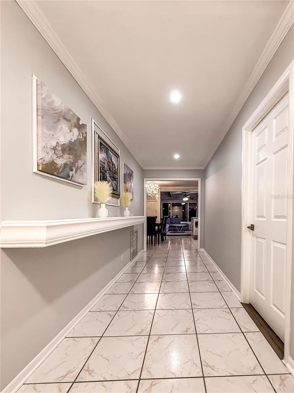 A hallway with light gray walls, white tile flooring, and a long floating shelf — 898 CORVETTE DRIVE, LARGO, FL
