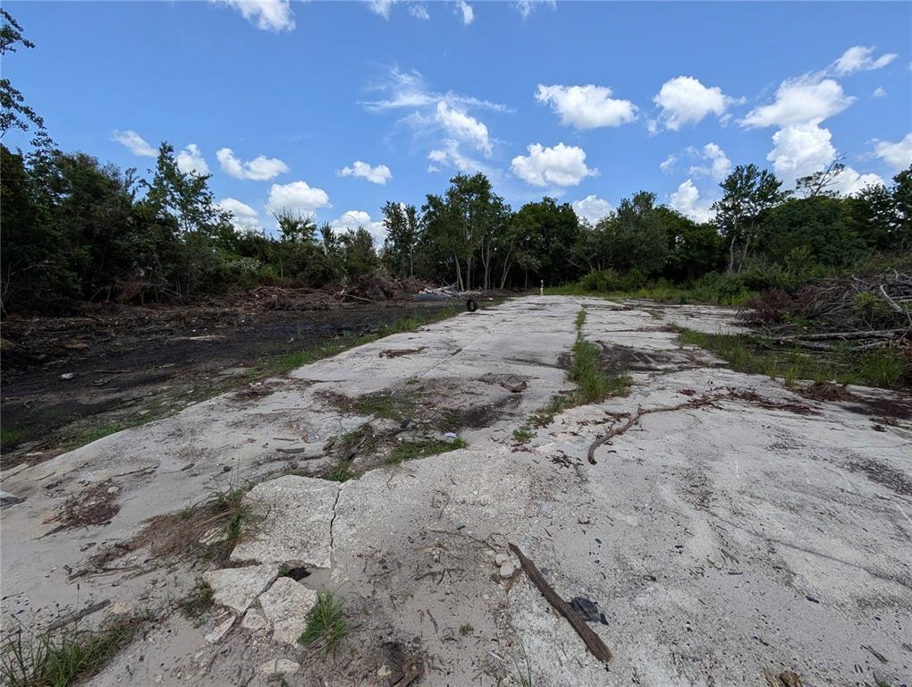 A concrete slab sits on a cleared lot surrounded by trees under a blue sky — 18847 JEFFERSON AVENUE, ORLANDO, FL