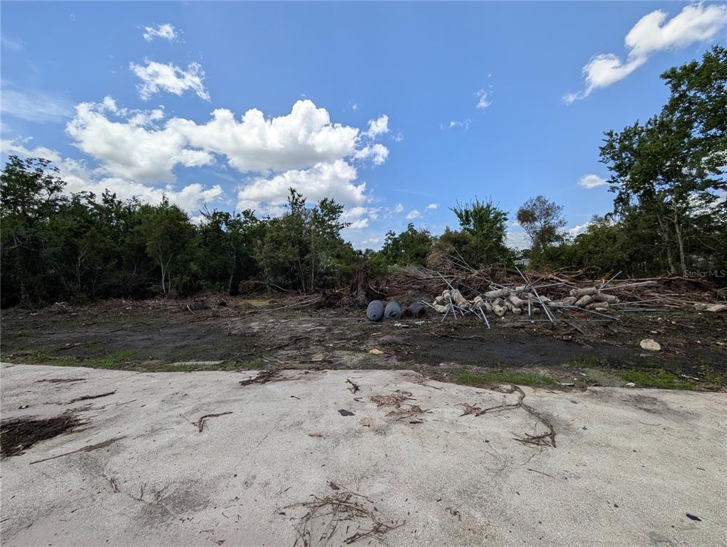A cleared, dirt-covered lot features a concrete slab in the foreground and scattered debris — 18847 JEFFERSON AVENUE, ORLANDO, FL