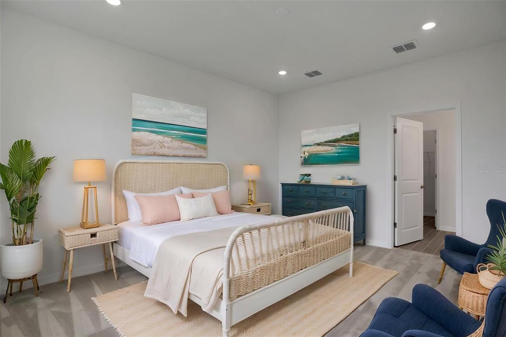 A bedroom features a wicker bed, two blue armchairs, a blue dresser, and coastal artwork — 8112 SUNNY POINT TRAIL, PARRISH, FL
