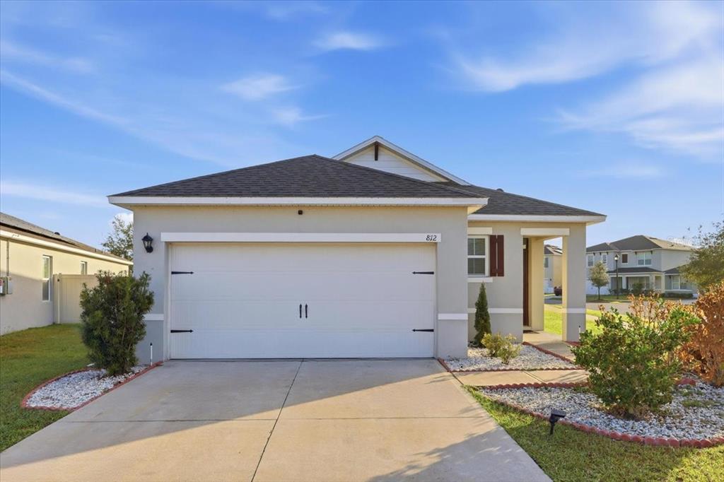 A single-story house with a white garage door, light gray siding, and a concrete driveway — 812 BROOKLET DRIVE, DAVENPORT, FL