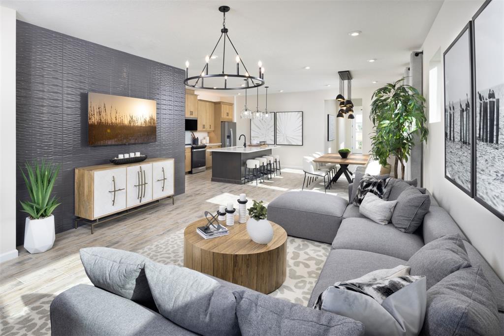 A modern open-concept living room features a textured dark accent wall and a gray sectional — 11423 BOUNDLESS TERRACE, VENICE, FL