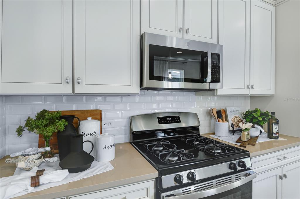 A kitchen features white cabinets, a stainless steel microwave, a gas stove, and subway tile — 5316 SPRING MAIDEN CIRCLE, APOLLO BEACH, FL