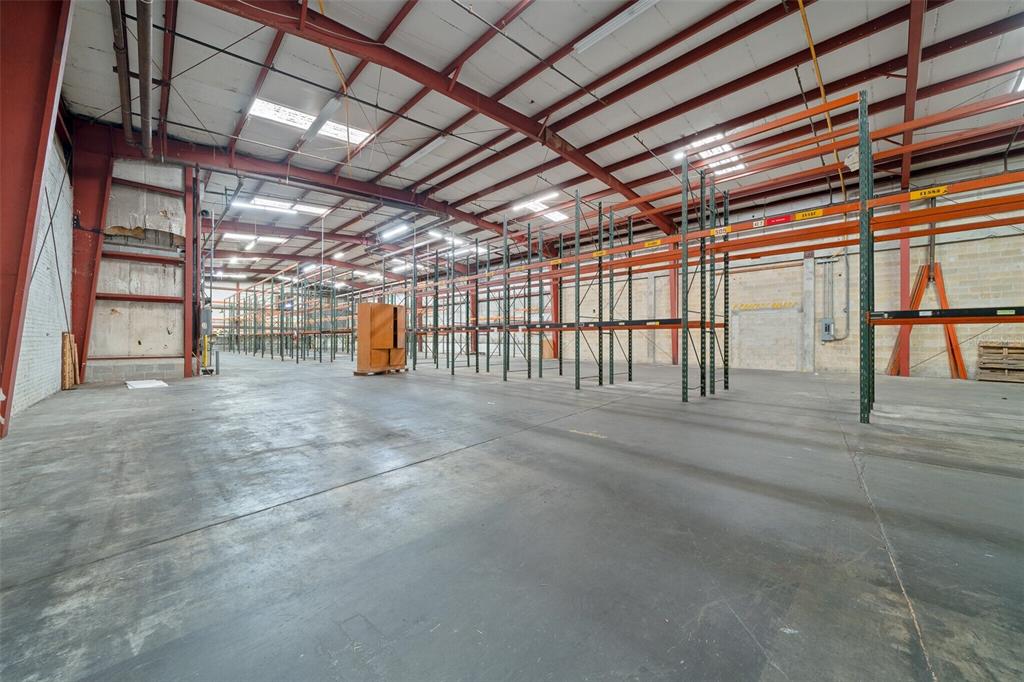 A large, empty warehouse space features high ceilings, concrete floors, and rows of metal shelving — 506 SE 3RD AVENUE, OCALA, FL