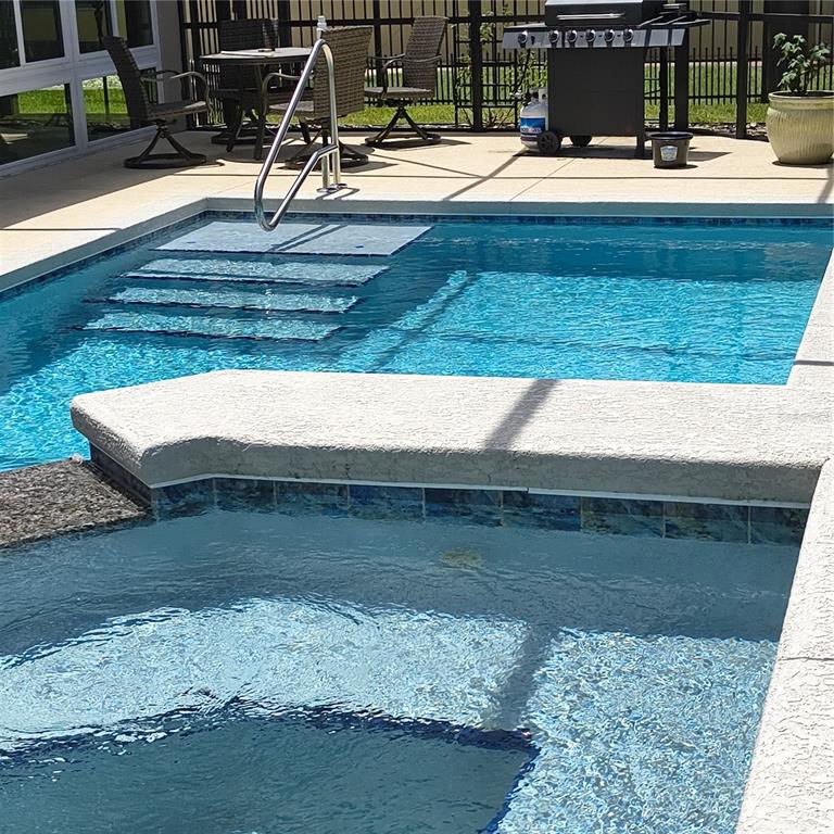 A swimming pool with an attached spa, patio furniture, and a grill on a pool deck — 9508 SW 66TH LOOP, OCALA, FL