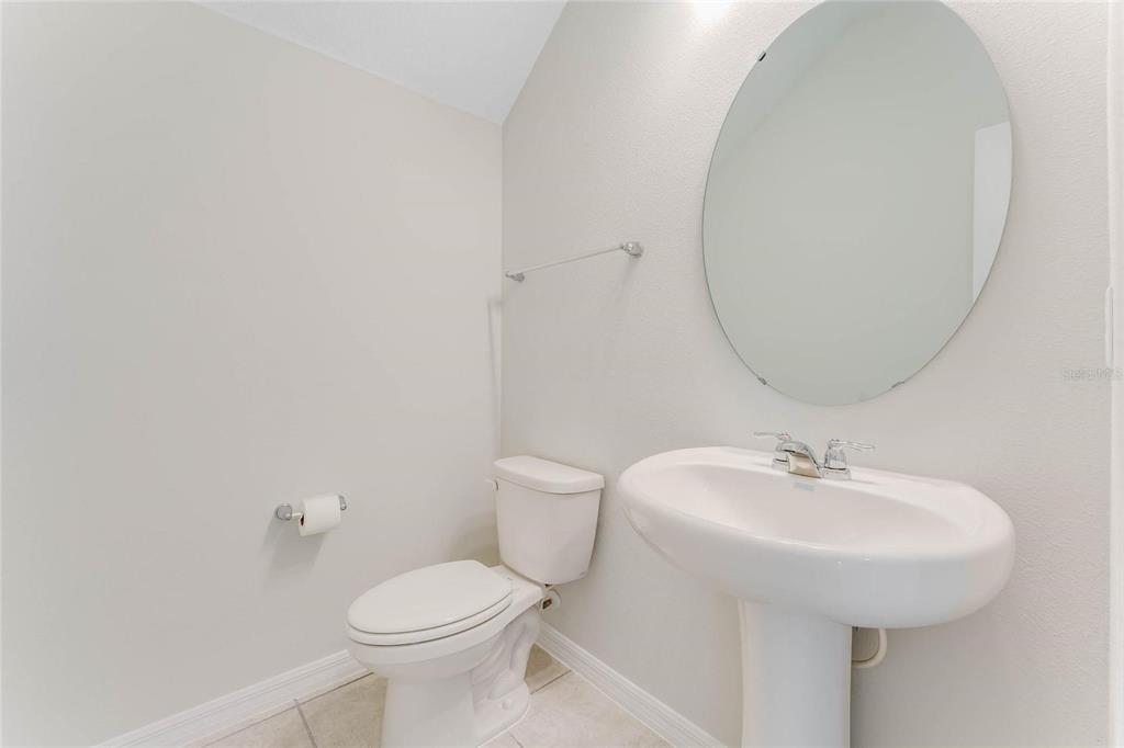 A small bathroom features a pedestal sink, an oval mirror, and a white toilet — 3716 ROLLING RIDGE BEND, DAVENPORT, FL