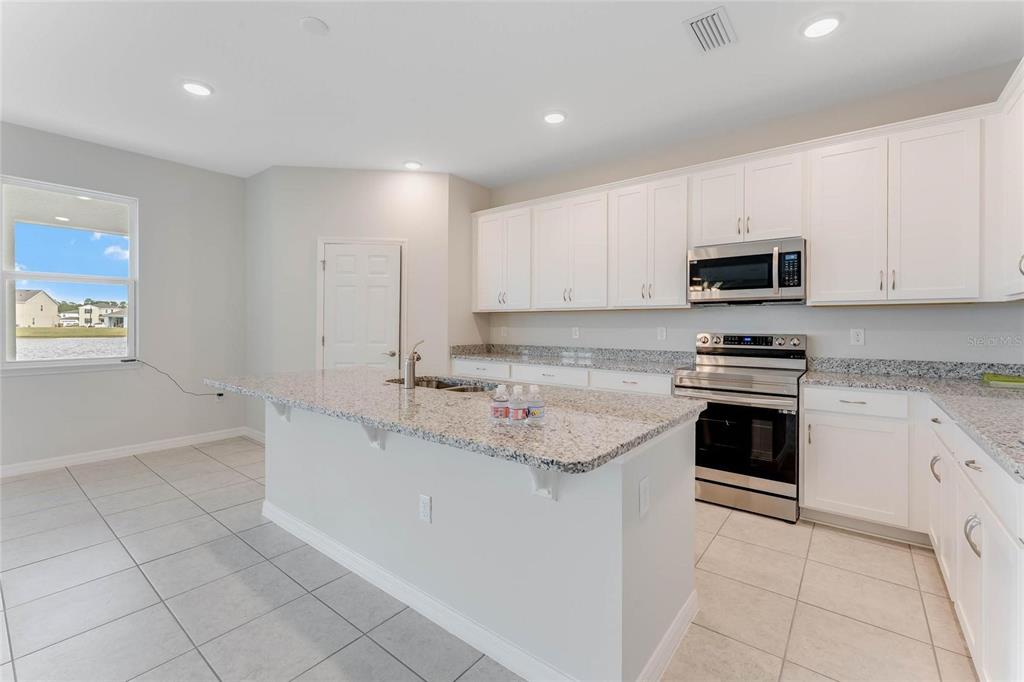 A kitchen with white cabinets, granite countertops, stainless steel appliances, and tile flooring — 3716 ROLLING RIDGE BEND, DAVENPORT, FL