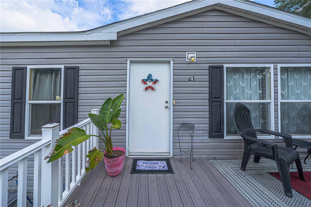 A gray-sided house exterior features a white front door, a porch, and a potted plant — 21 NE 69TH COURT, OCALA, FL