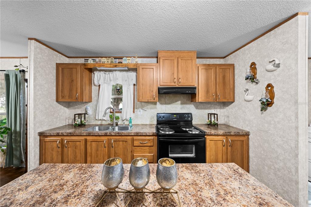 A kitchen features wood cabinets, laminate countertops, a black stove, and a central island — 21 NE 69TH COURT, OCALA, FL