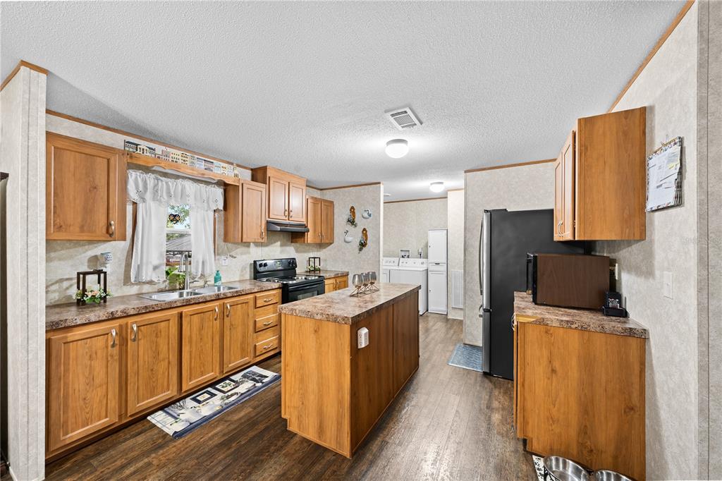 A kitchen features wood cabinets, a center island, laminate countertops, and a black refrigerator — 21 NE 69TH COURT, OCALA, FL