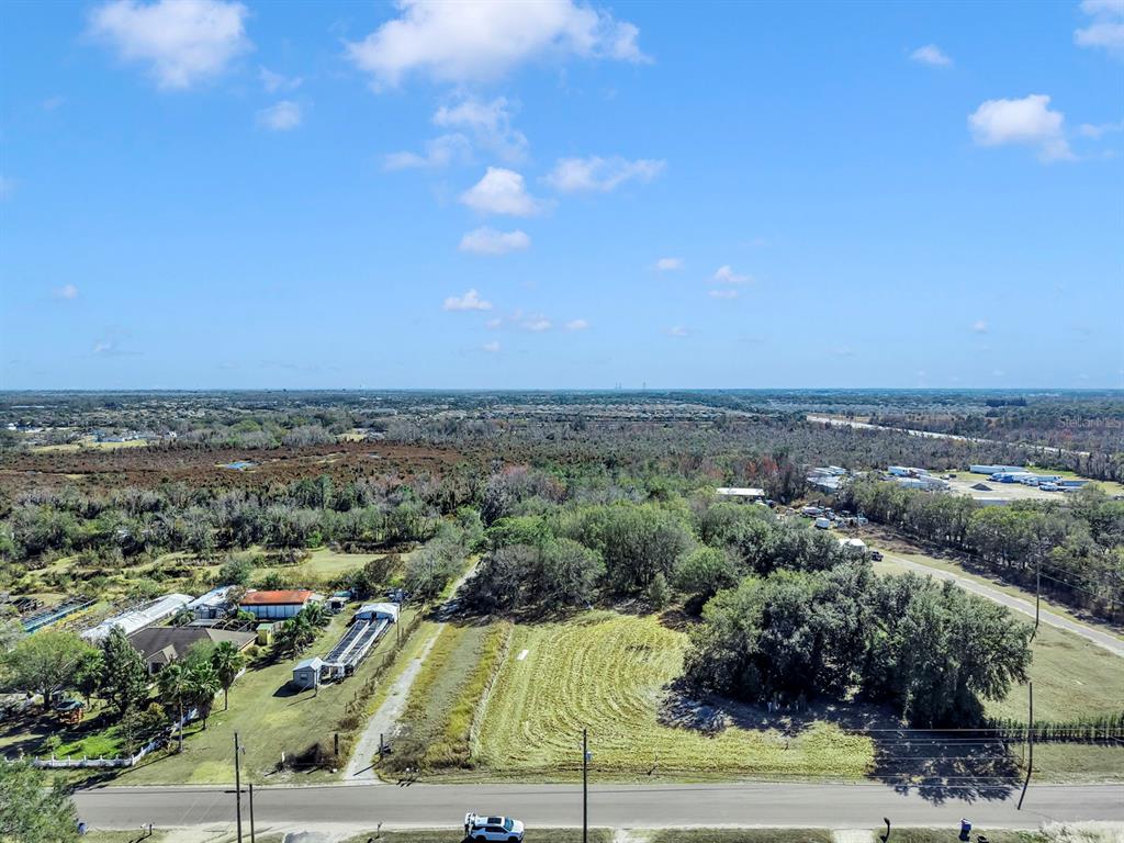 An aerial view shows a rural lot with trees, a small structure, and a paved road — 10611 SUMNER ROAD, WIMAUMA, FL