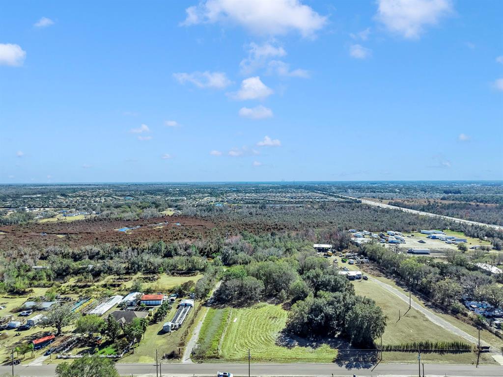 An aerial view shows a rural property with trees, structures, and a road in Florida — 10611 SUMNER ROAD, WIMAUMA, FL