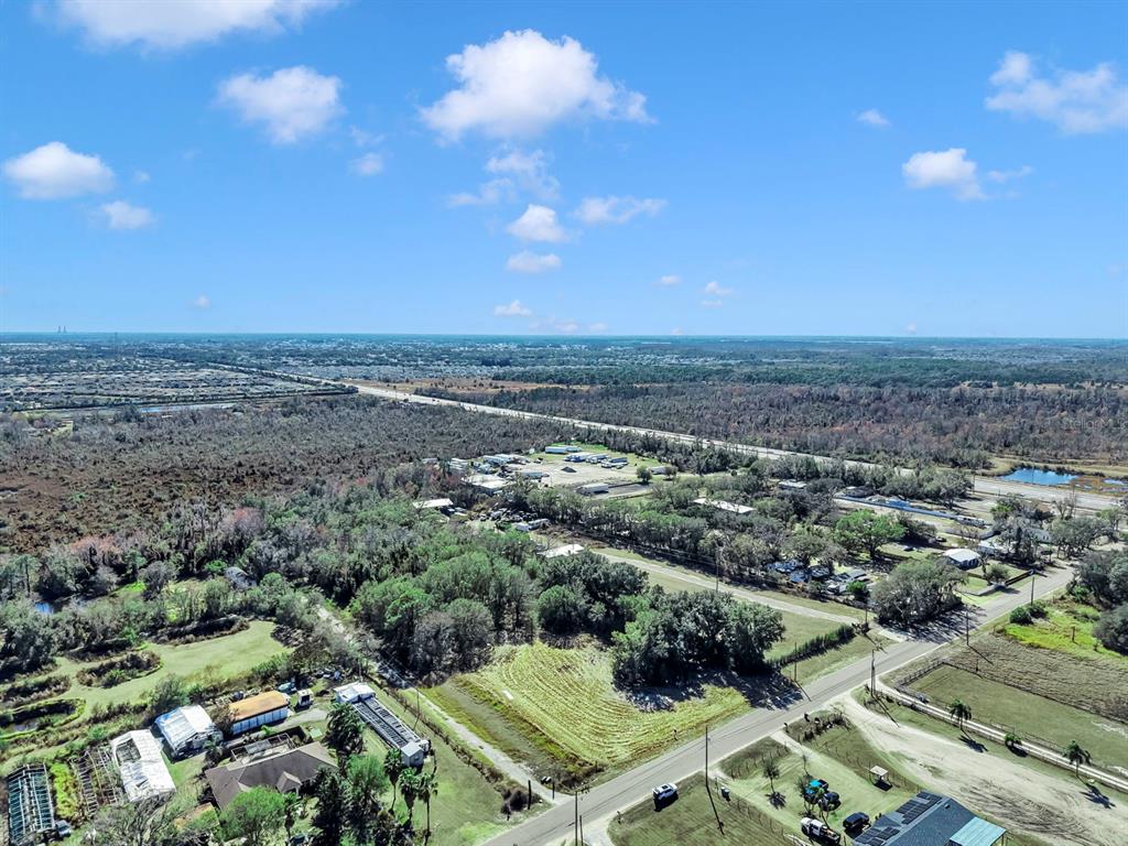 An aerial view shows a rural landscape with a highway, scattered buildings, and wooded areas — 10611 SUMNER ROAD, WIMAUMA, FL