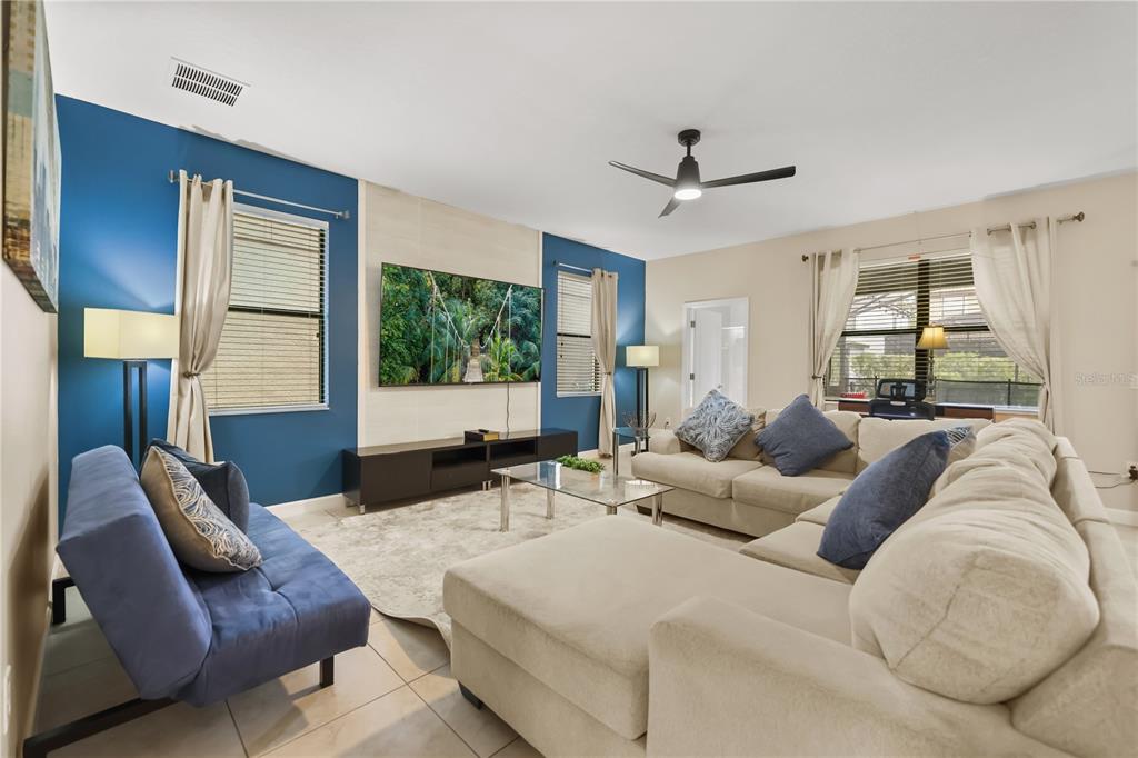 A living room features a blue accent wall, a large television, and beige sectional seating — 1423 THUNDERBIRD ROAD, DAVENPORT, FL