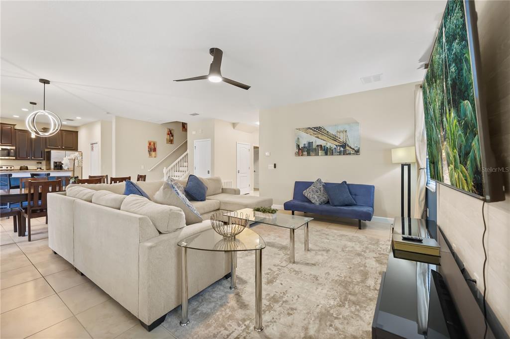 A living room features a large sectional sofa, a blue futon, and a wall-mounted television — 1423 THUNDERBIRD ROAD, DAVENPORT, FL