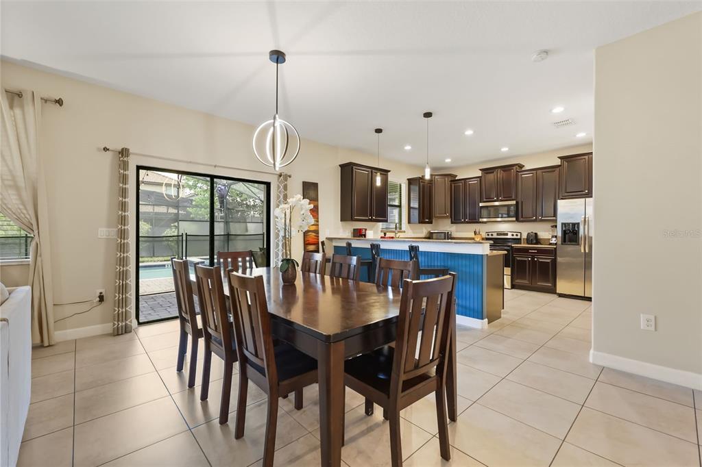 A dining area with a wooden table and chairs opens to a kitchen with dark cabinetry — 1423 THUNDERBIRD ROAD, DAVENPORT, FL