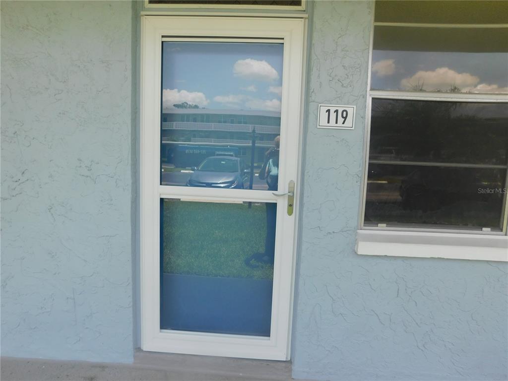 A white storm door with a glass panel is mounted on a light blue wall — 4715 BAY STREET NE UNIT 119, ST PETERSBURG, FL