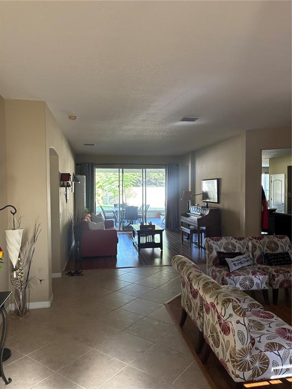 A living room features tile flooring, a piano, and a sliding glass door to a patio — 307 CARRIAGE OAK PL, SEFFNER, FL
