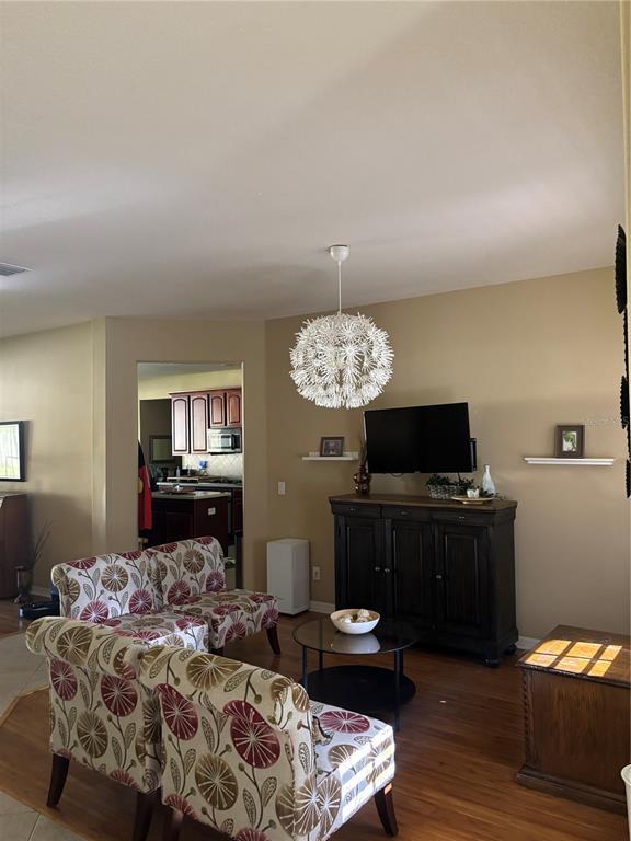 A living room features patterned armchairs, a dark wood media console, and a spherical pendant light — 307 CARRIAGE OAK PL, SEFFNER, FL