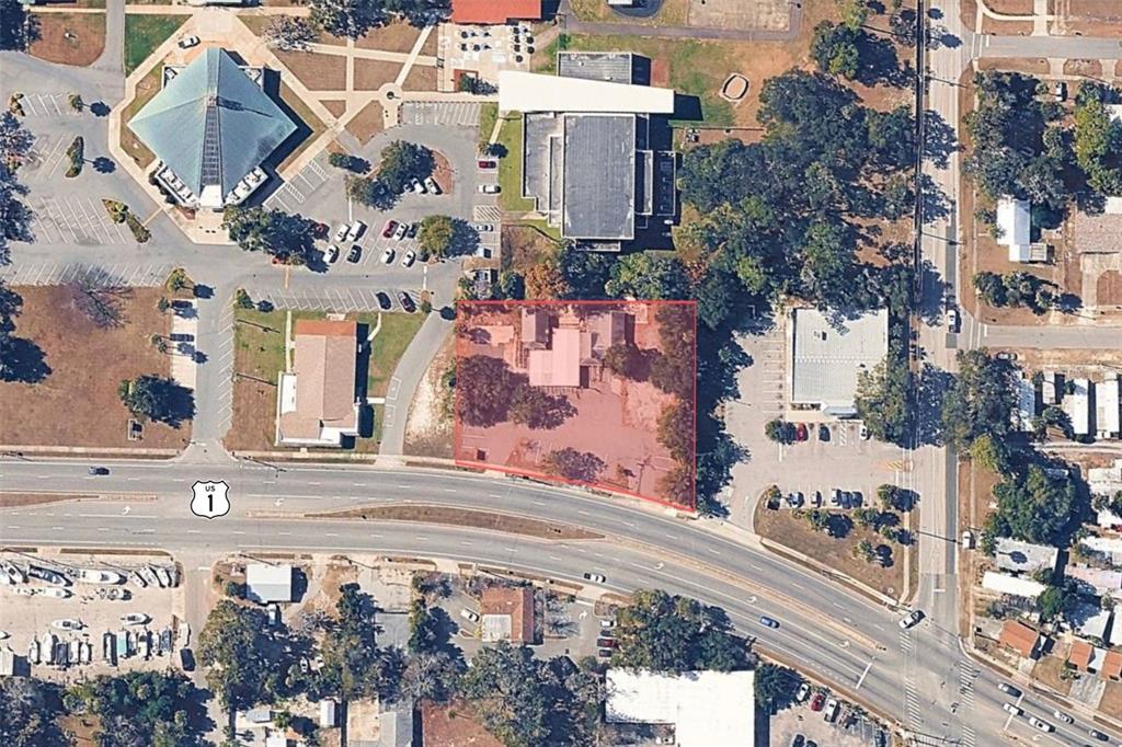 An aerial view shows a rectangular property lot highlighted in red along a curved highway — 1042 N DIXIE FREEWAY, NEW SMYRNA BEACH, FL