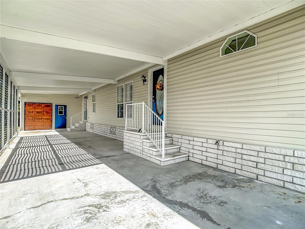 A blue front door with an oval glass insert and a wreath sits on a porch — 5745 PAWNEE STREET, ZEPHYRHILLS, FL