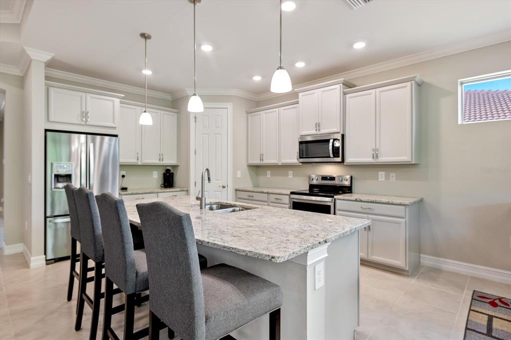 A kitchen features white cabinets, granite countertops, a center island with bar seating, and appliances — 520 MARAVIYA BOULEVARD, NOKOMIS, FL