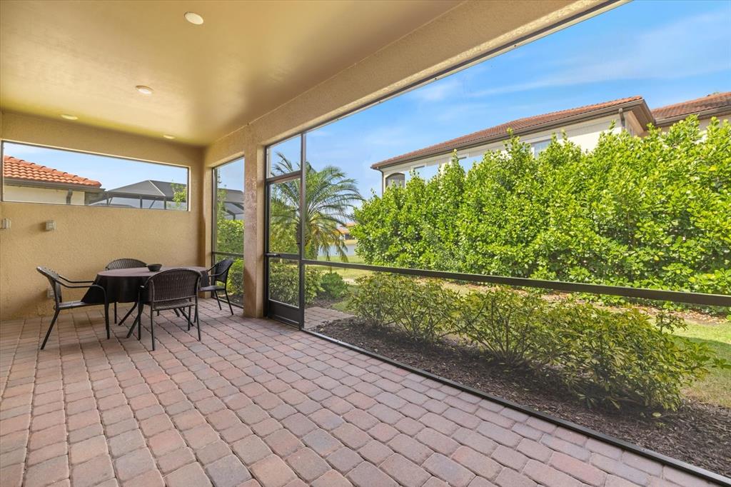 A covered patio with brick pavers, a dining set, and a screened view of landscaping — 520 MARAVIYA BOULEVARD, NOKOMIS, FL