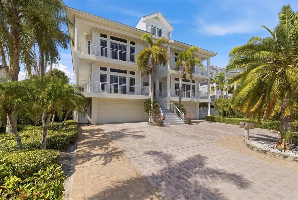 A three-story white house with a paved driveway, palm trees, and a front staircase — 24 N PINE CIRCLE, BELLEAIR, FL