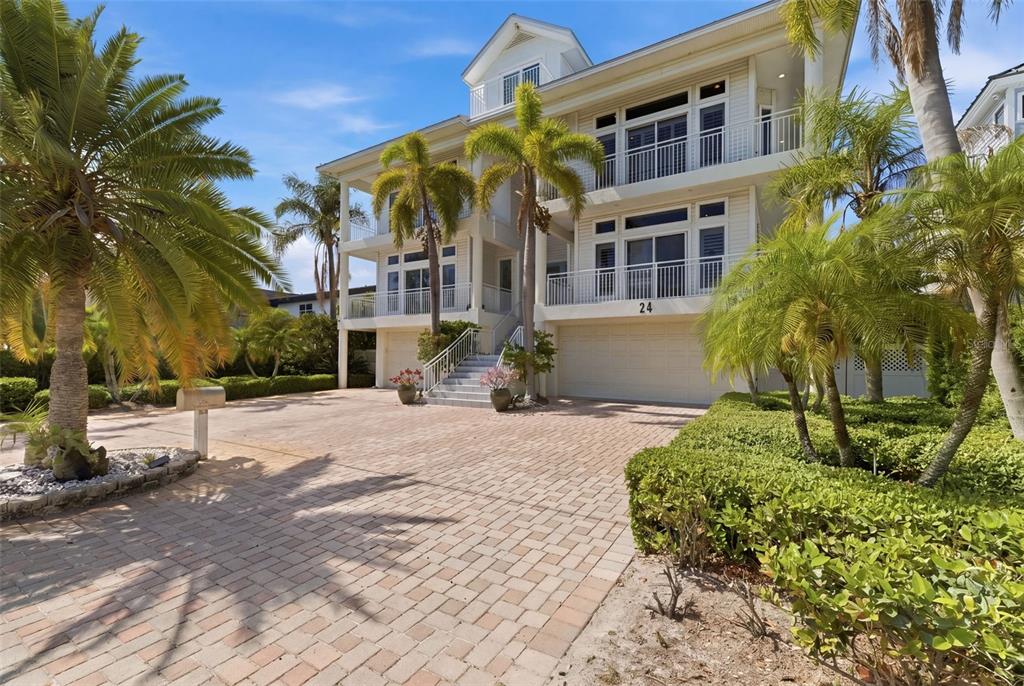 A three-story white house with a paved driveway and palm trees in the front yard — 24 N PINE CIRCLE, BELLEAIR, FL