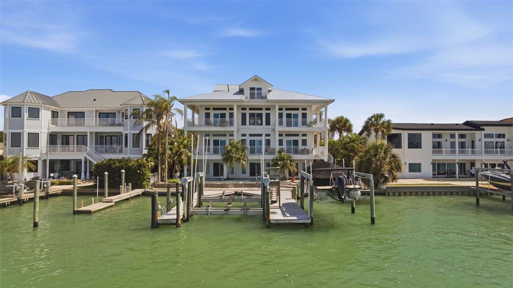 A three-story waterfront house with a private boat dock and palm trees on a canal — 24 N PINE CIRCLE, BELLEAIR, FL
