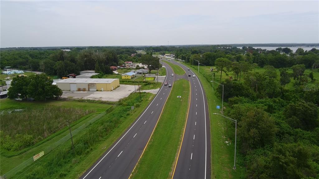 An aerial view shows a wooded lot bordering a lake next to a paved road — 0 ALFRED DRIVE E, LAKE ALFRED, FL